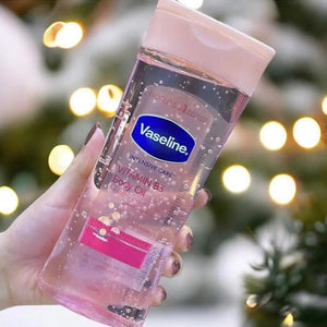 Vaseline body oil bottle held in a hand with a blurred festive background