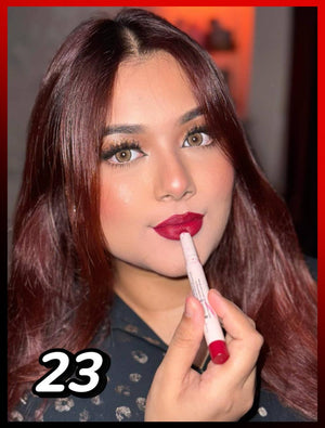 Woman with brown eyes and red hair applying deep red lipstick, beauty makeup close-up