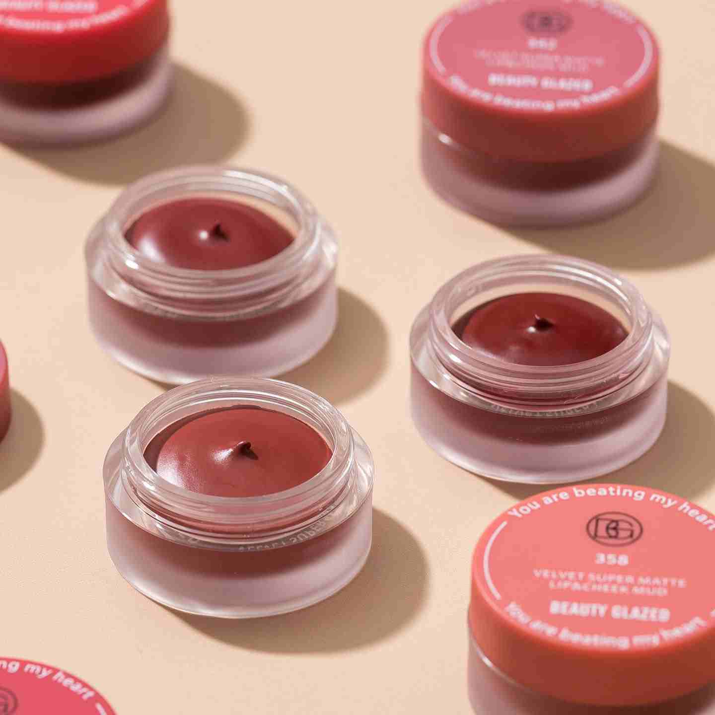 Beauty Glazed velvet super matte lip and cheek blur in red shades with clear glass jars and coral lids